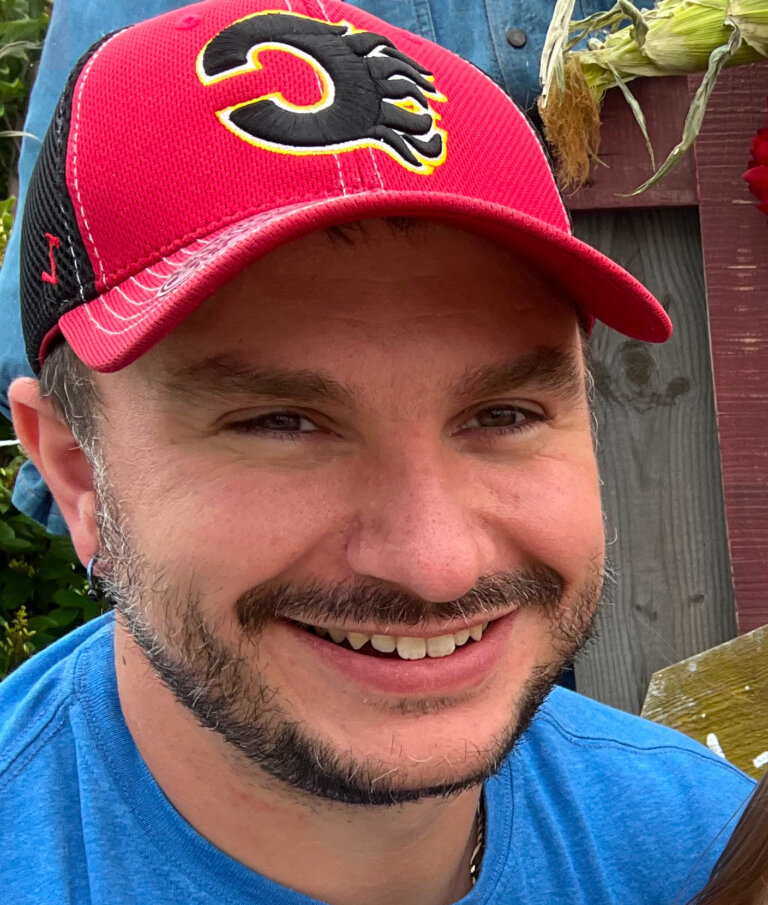 A man with facial hair wearing a Calgary Flames baseball cap